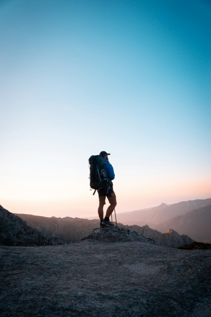 Hiker with a large backpack on a rocky peak at golden hour