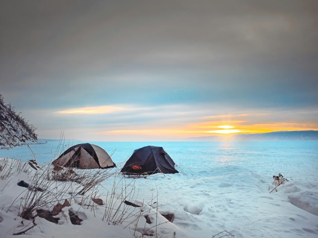 Dark tent pitched on snow at sunset